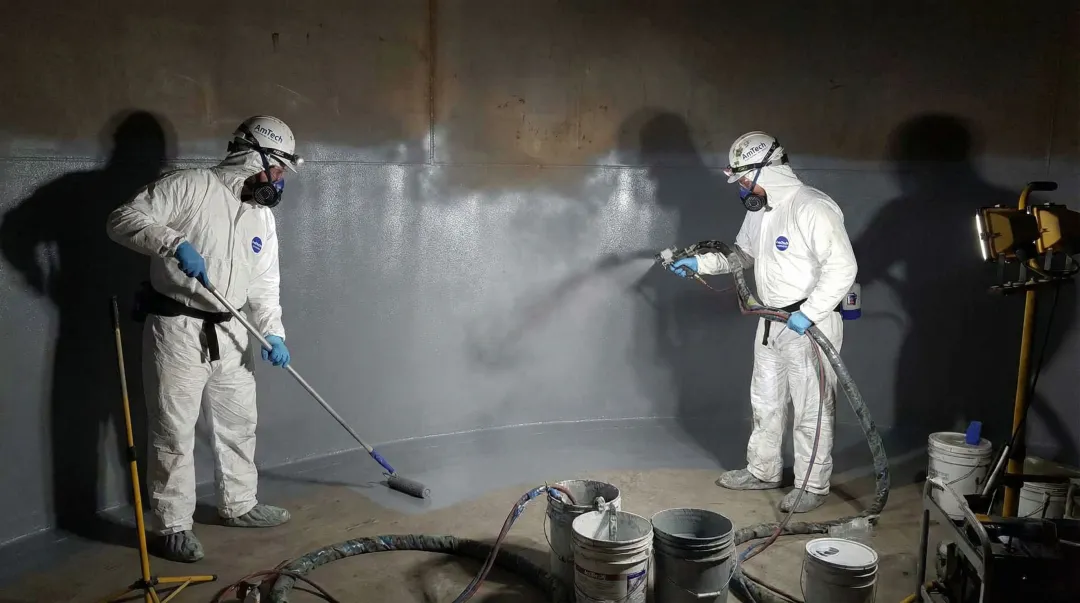 Tank lining application crew applying protective coating inside large atmospheric storage tank
