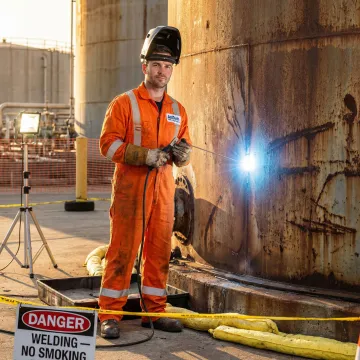 Emergency oil tank repair technician performing urgent leak repair on industrial petroleum storage tank