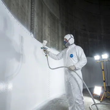 Technician applying protective lining to repaired water storage tank interior