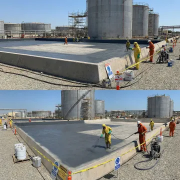 Industrial crew installing chemical-resistant containment liner around storage tanks