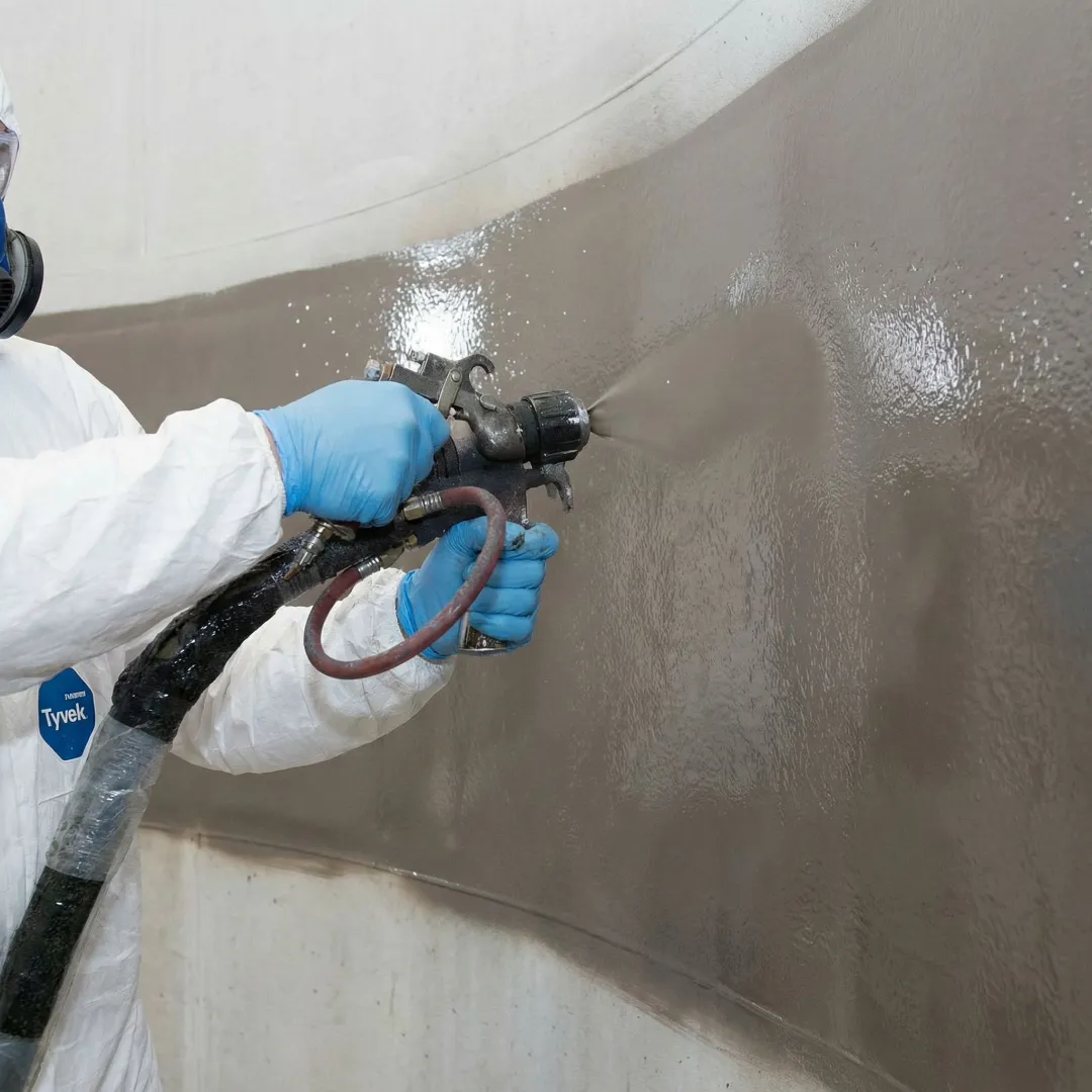 Tank maintenance technician applying protective coating system inside industrial storage tank