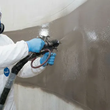 Tank maintenance technician applying protective coating system inside industrial storage tank