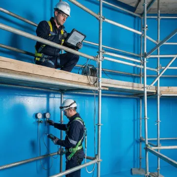 Industrial tank maintenance technicians performing inspection on large storage tank