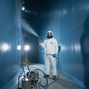 Field technician applying instant-cure tank lining to repair damaged fuel storage tank interior
