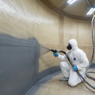 Technician applying DuraChem polylining to interior of FRP wastewater tank