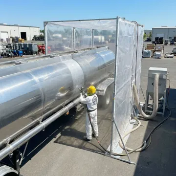 Professional sandblasting crew preparing tank truck surface in Bakersfield facility