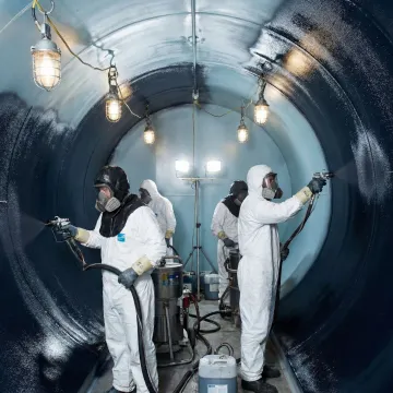 Industrial tank interior being spray-coated with protective rubber lining system