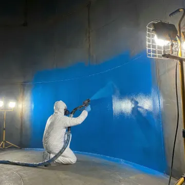AmTech technician applying protective coating to commercial propane tank interior