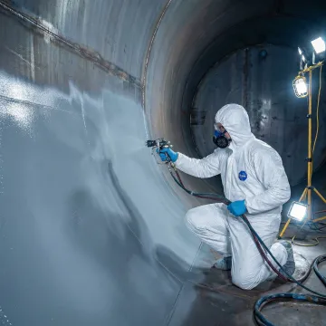 Technician applying protective coating to commercial propane tank interior