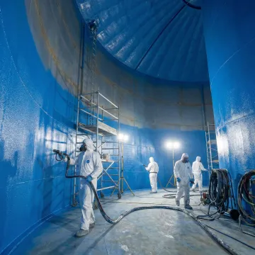 Emergency hot water tank repair crew applying instant-cure lining system inside industrial tank