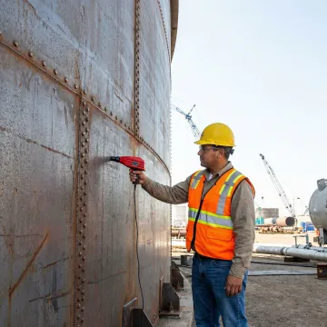 Technician performing ultrasonic testing on industrial storage tank