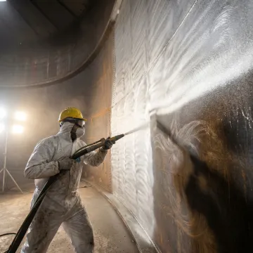 Professional abrasive blasting crew preparing industrial storage tank interior surface
