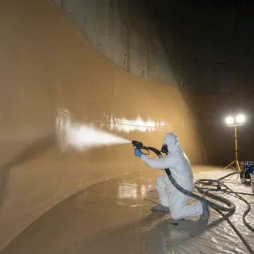 Technician applying protective coating to repaired oil tank interior