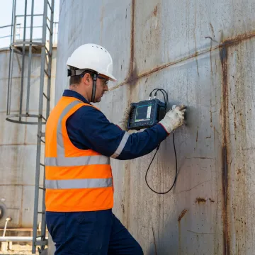 Technician performing ultrasonic leak detection on industrial storage tank