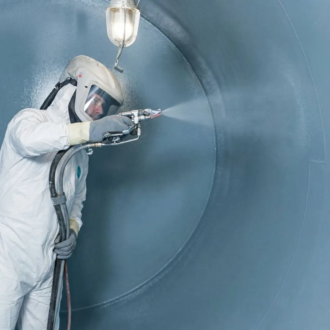 Technician applying industrial tank coating with spray equipment