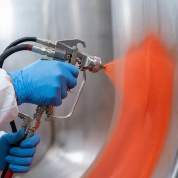 AmTech technician spray-applying DuraChem tank lining system inside industrial storage tank