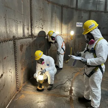 Crew inspecting and lining a wastewater tank interior