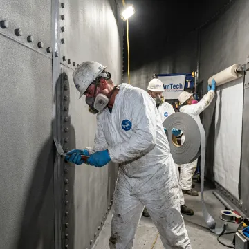 Crew sealing seams inside a bolted steel tank