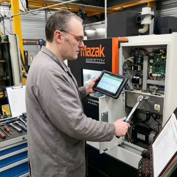A.W. Miller technician performing step-by-step CNC machine repair in an industrial workshop