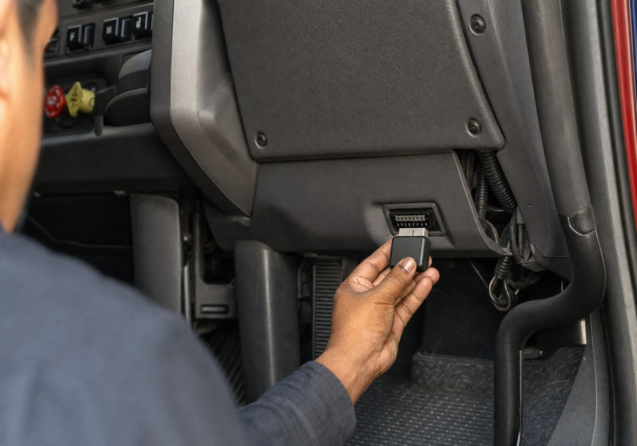 Truck driver installing plug-and-play OBD-II ELD device in cab