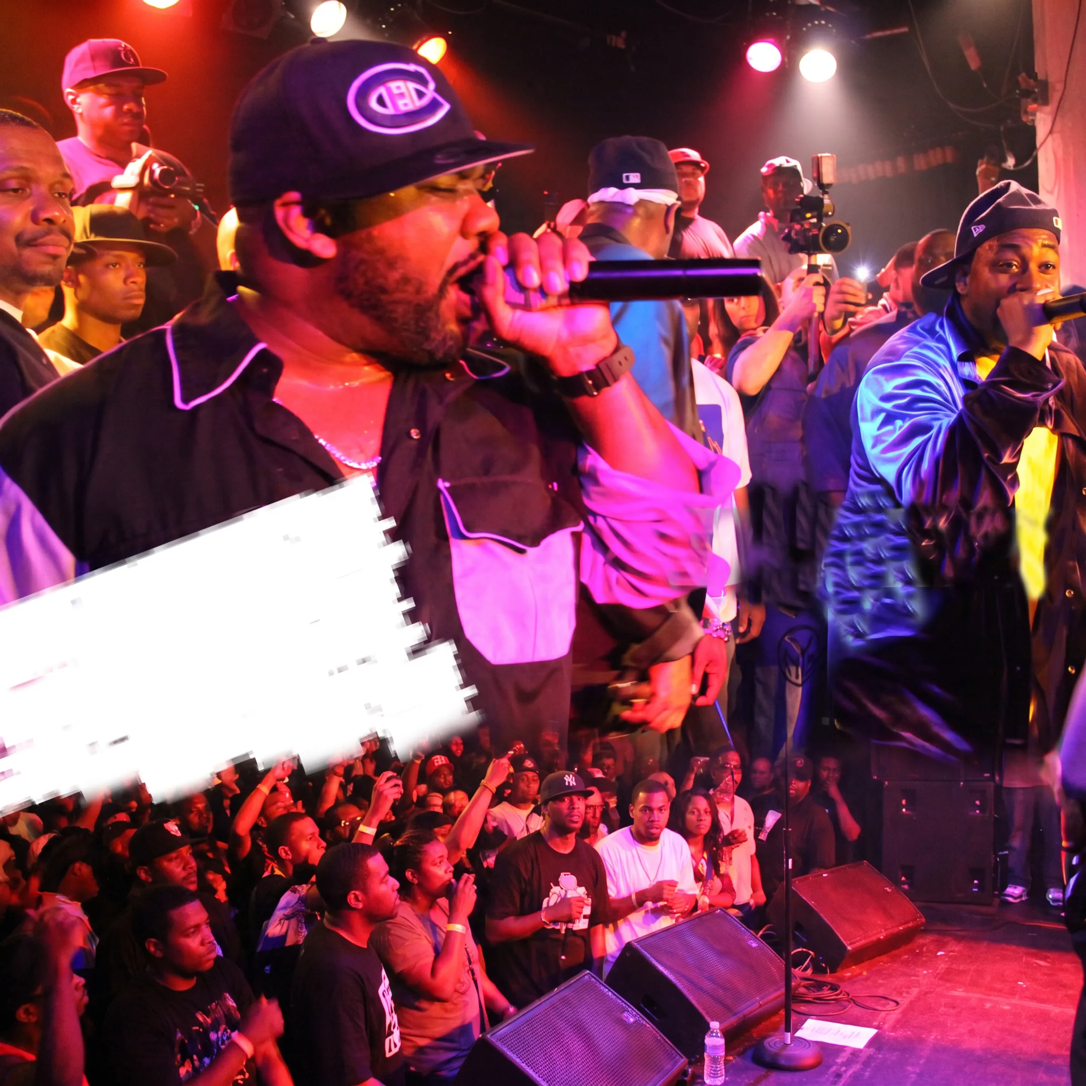 Hip-hop artist performing live on stage with microphone under vibrant concert lighting