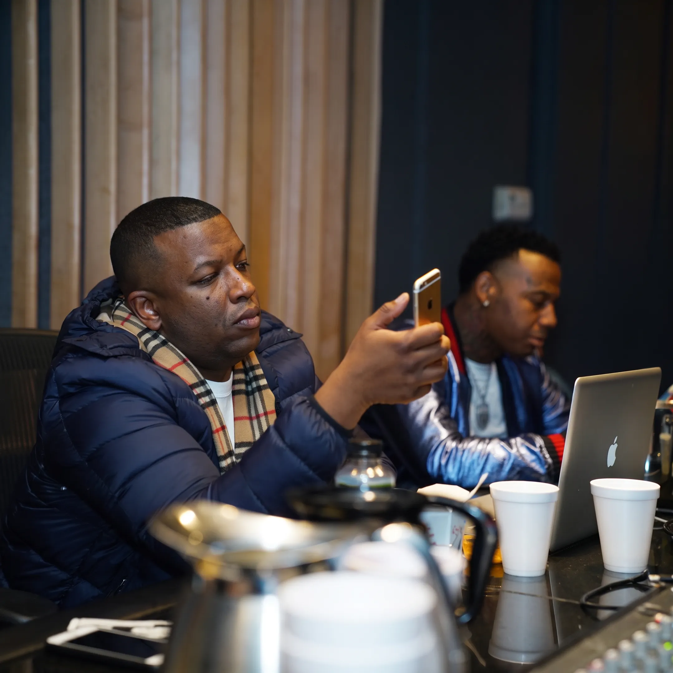 Hip-hop artist and manager discussing music career strategy in a professional studio
