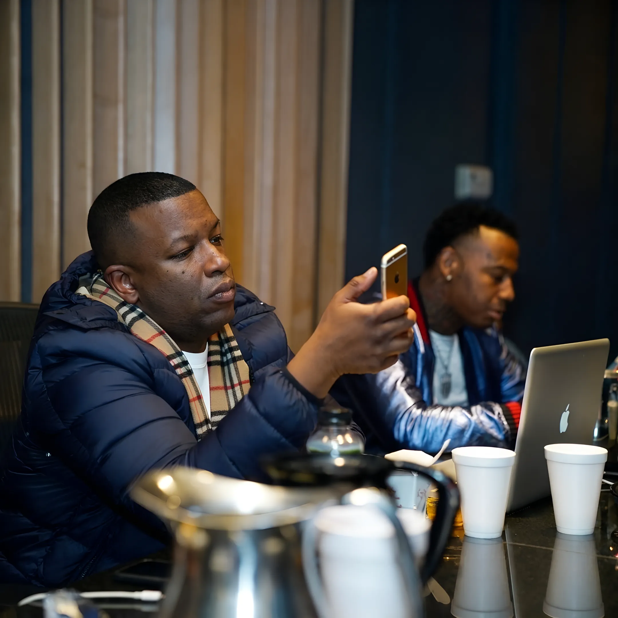Independent hip-hop artist recording music while reviewing promotional campaign materials with an entertainment consultant