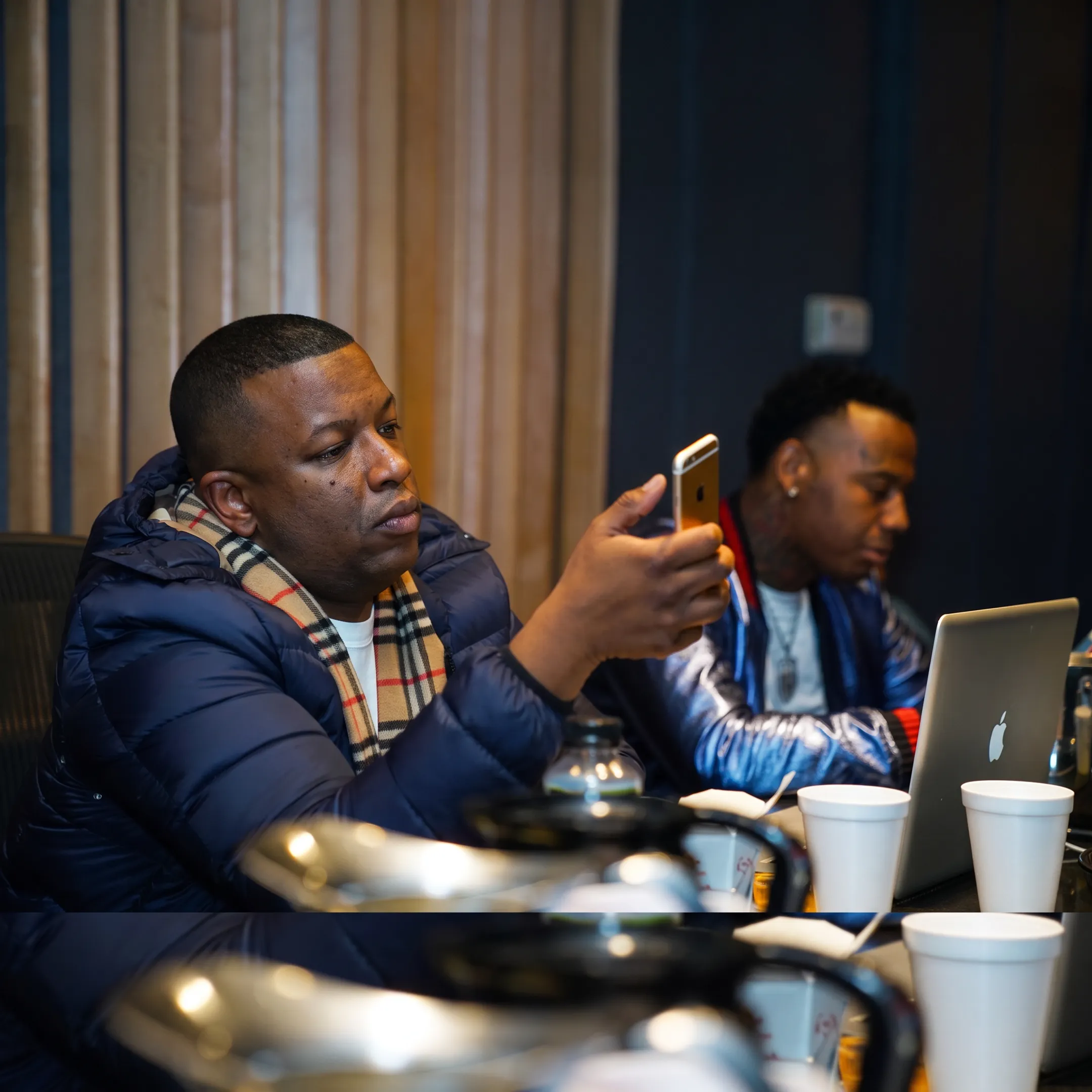 Hip-hop artist recording music while reviewing a promotion strategy with an entertainment consultant