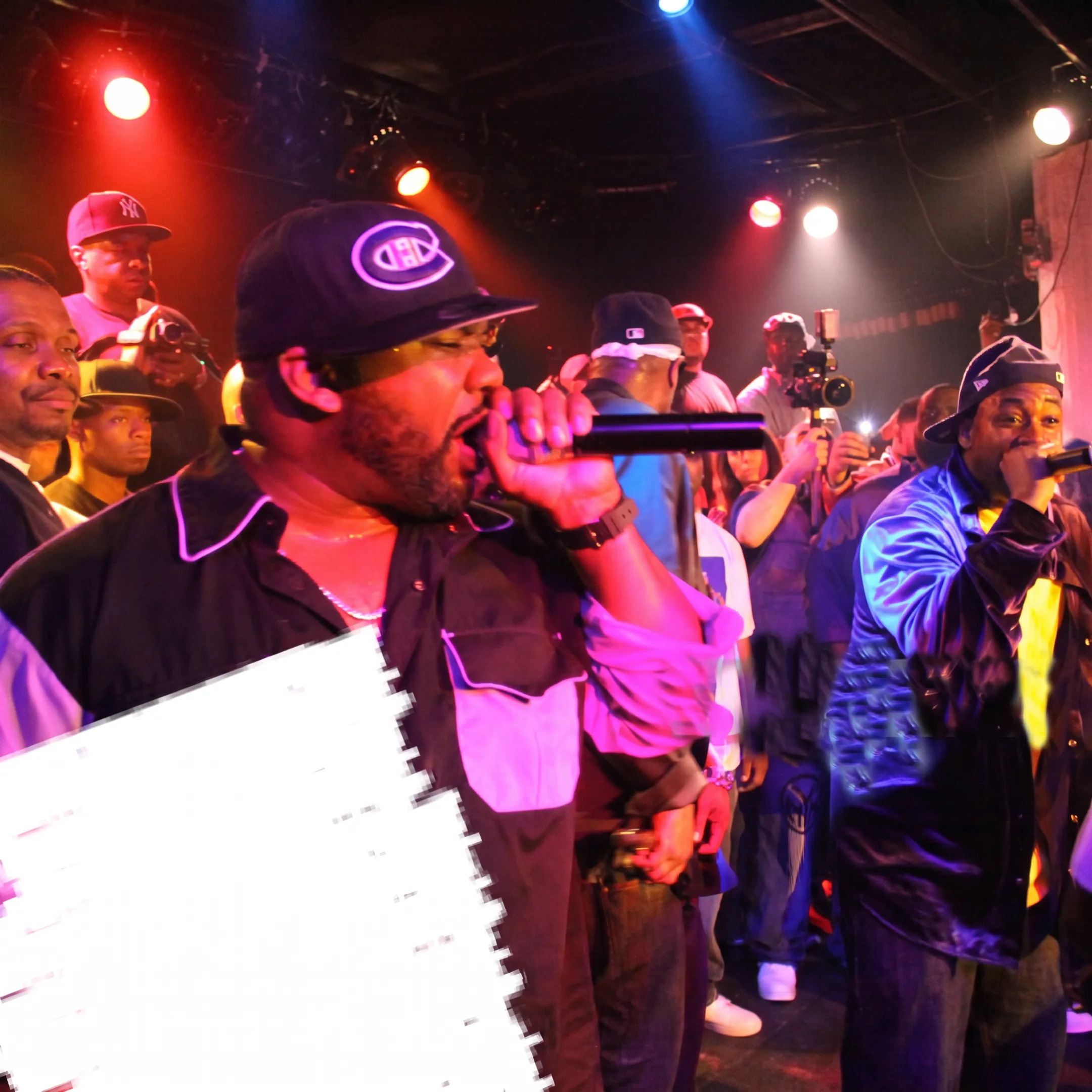 Rapper performing onstage before an engaged crowd at a live music venue