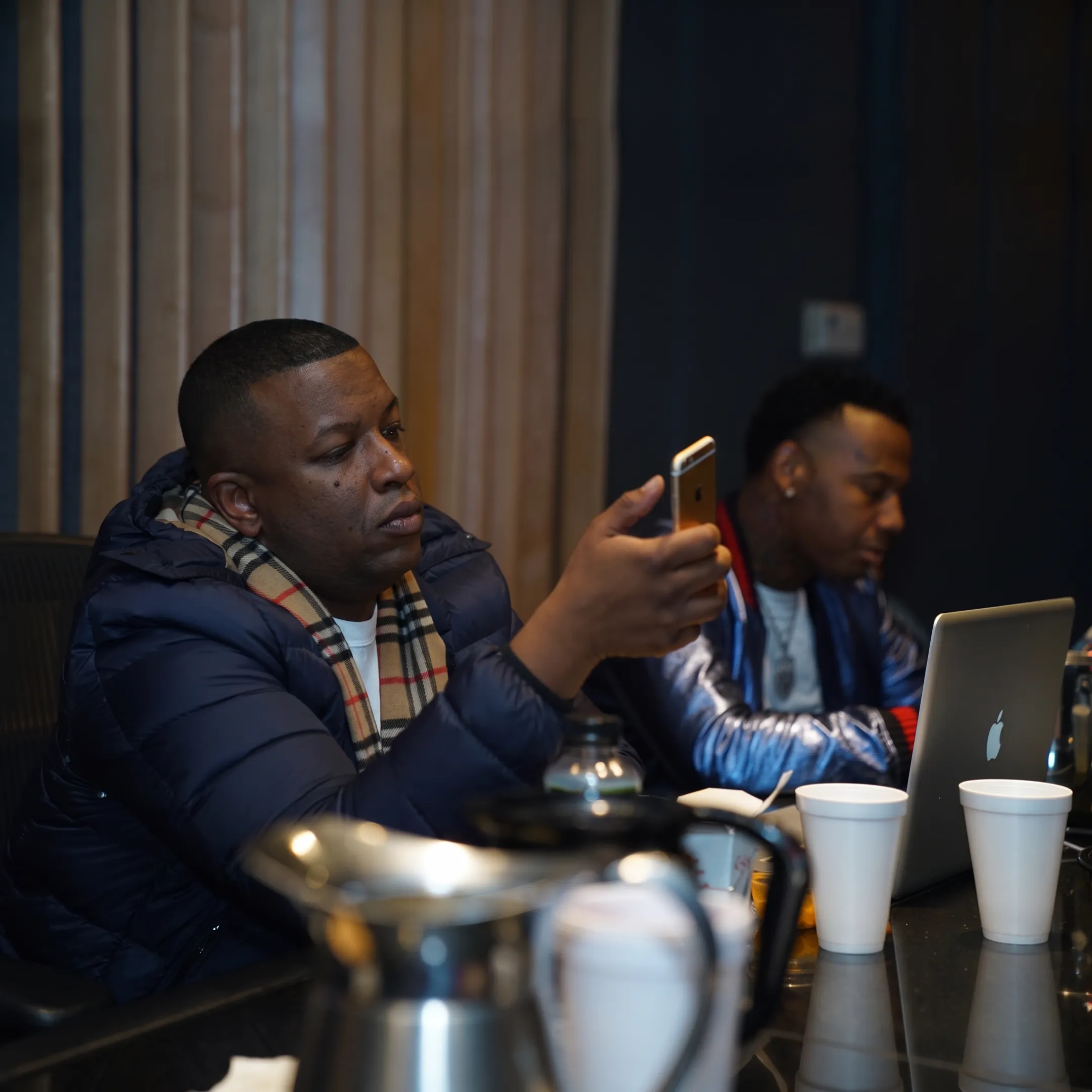 Hip hop artist recording music while a promotion team reviews release strategy in a studio