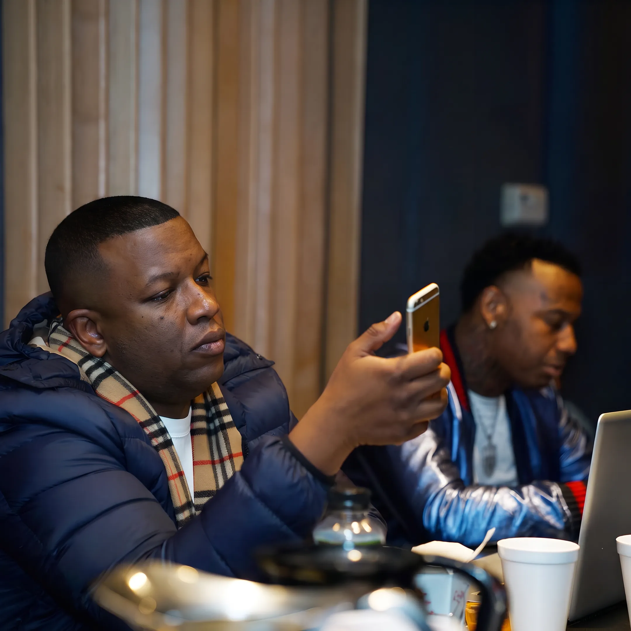 Hip hop artist recording music while a promotion team reviews campaign materials in a creative studio