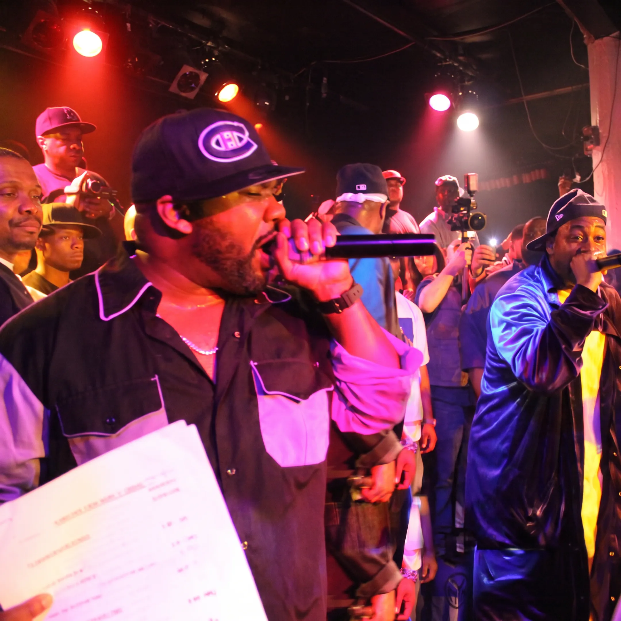 Independent artist performing onstage while a booking professional coordinates live music opportunities