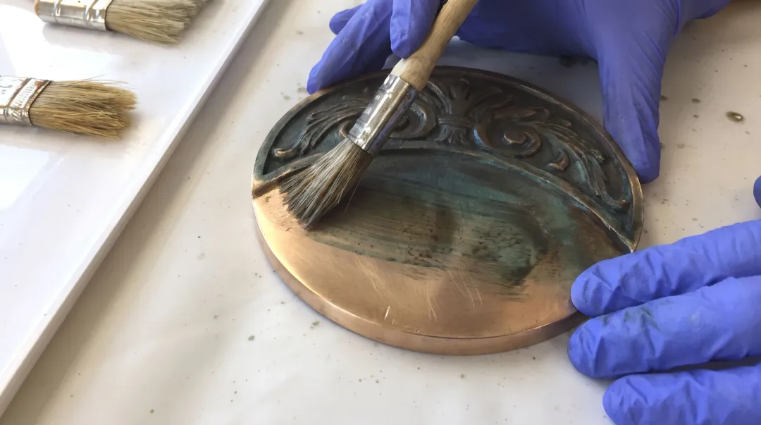 Bronze sculpture surface showing chemical patina application with visible tone variation
