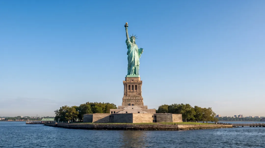 Statue of Liberty standing tall against New York harbor skyline