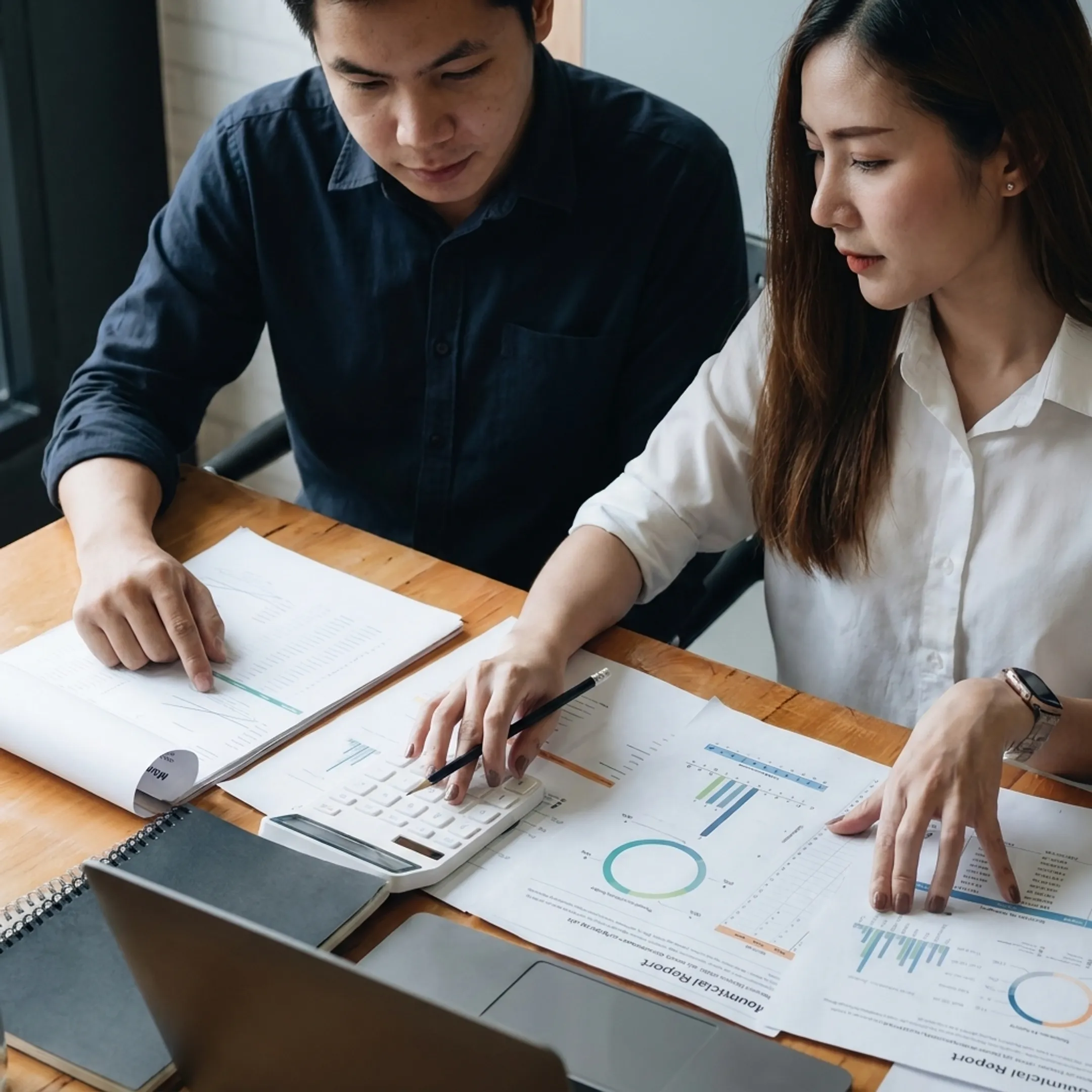 Business valuator reviewing financial documents with a business owner in a professional office