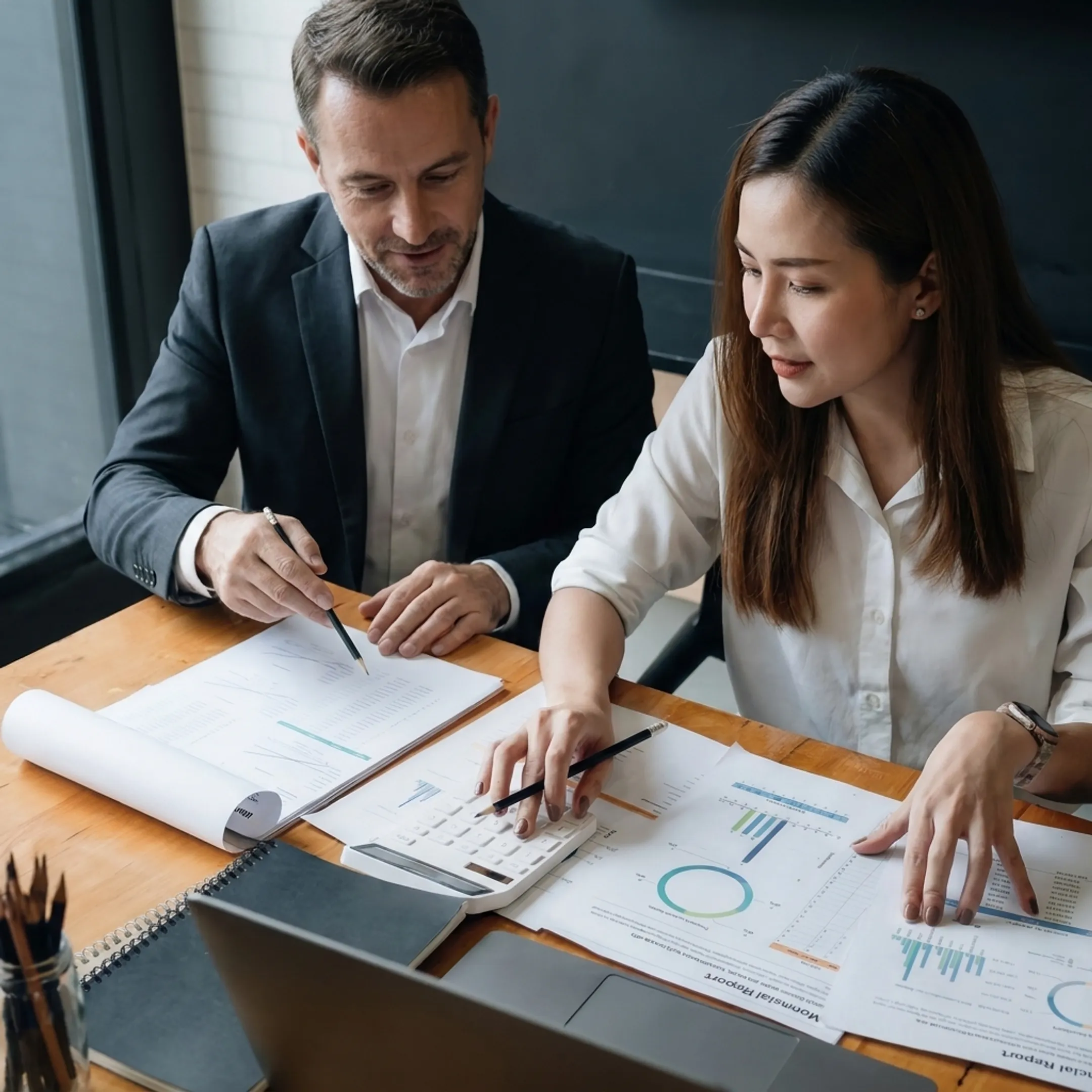 Business valuator reviewing financial documents with a business owner in an office