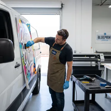 Technician applying vinyl graphics to a business van