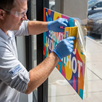 Custom vinyl sign being applied to a storefront window