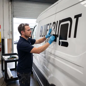 Technician applying vinyl lettering to a van