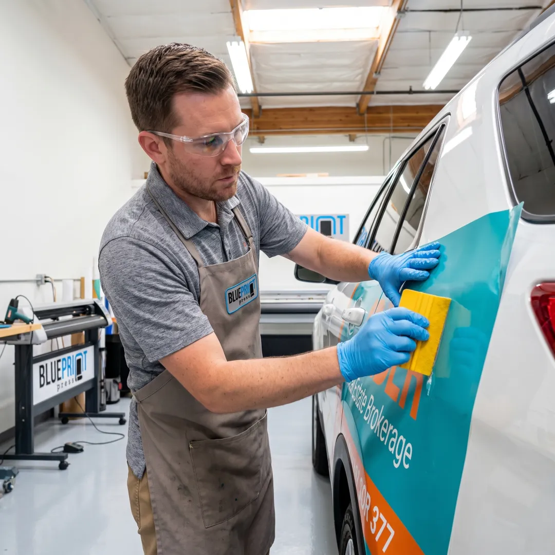 Technician applying a branded vinyl vehicle wrap