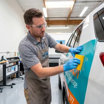Technician applying a branded vinyl vehicle wrap