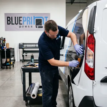 Designer applying custom vinyl graphics to a van