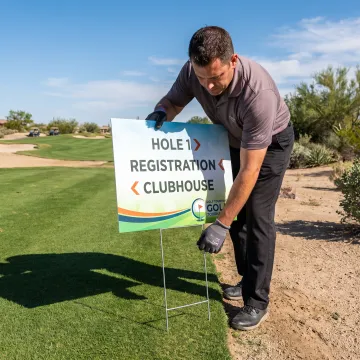 Golf tournament staff placing a branded yard sign