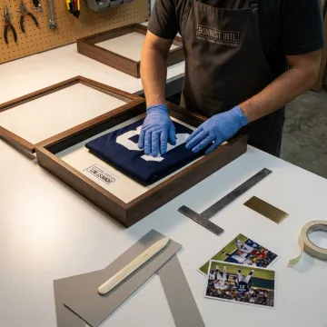 Craftsperson arranging a jersey for custom framing