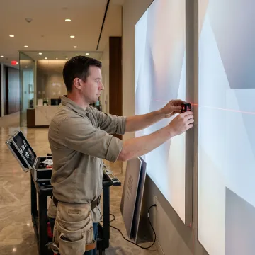 Fabricator installing illuminated wall art display