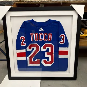 Craftsperson arranging a jersey for custom framing