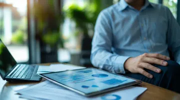 Passive investor reviewing franchise performance reports and financial dashboards on laptop in modern office