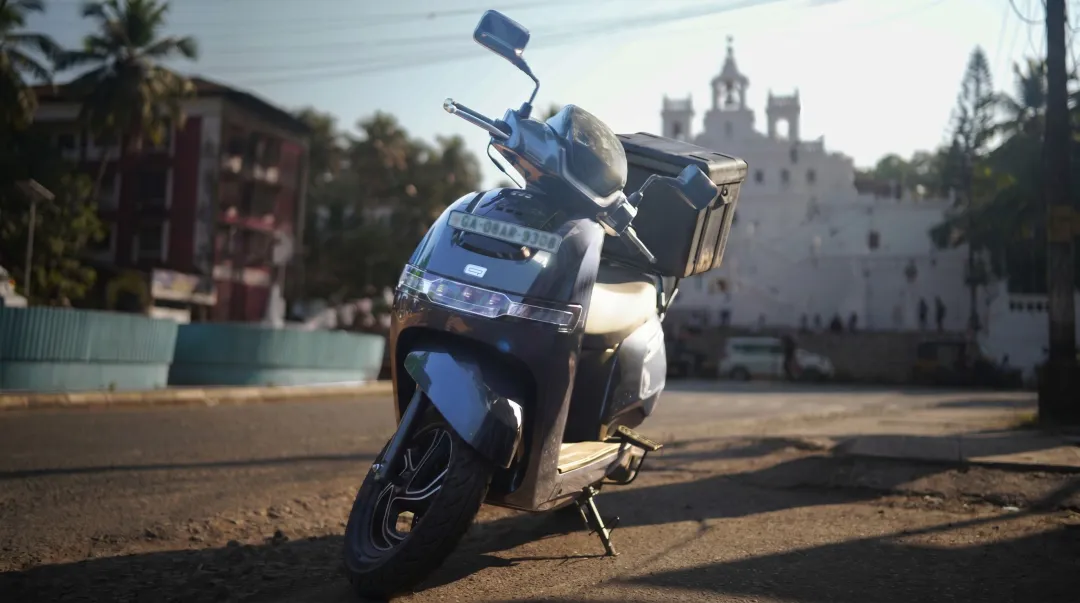 TVS iQube electric scooter parked on urban street with delivery bag