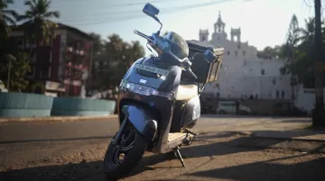 TVS iQube electric scooter parked on urban street with delivery bag