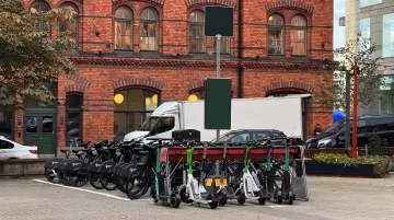 Electric scooter rental hub with EV fleet parked and charging at urban location